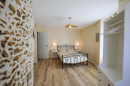 a bedroom with a bed and a stone wall at Le Logis du Beffroi in Sancerre
