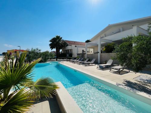 a swimming pool with lounge chairs and a house at Apartments and Rooms Mateša in Vodice