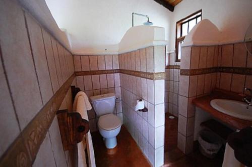a small bathroom with a toilet and a sink at Kiboko Lodge in Usa River