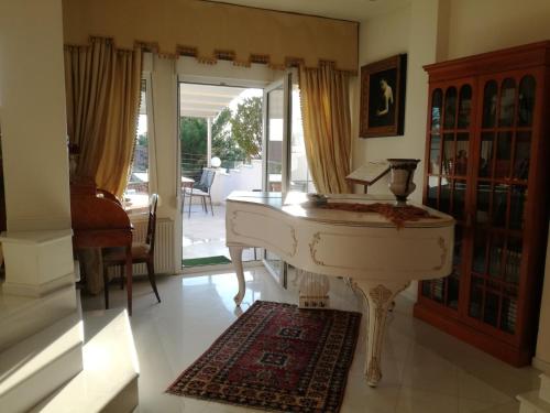 a white piano in a living room with a porch at Πολυτελής κατοικία με θέα τον Θερμαϊκό in Thessaloniki