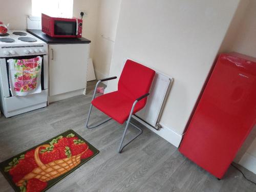 a red chair in a kitchen with a plate of strawberries at The Cosy 2 bedroom flat, sleeps 6 in Hebburn-on-Tyne