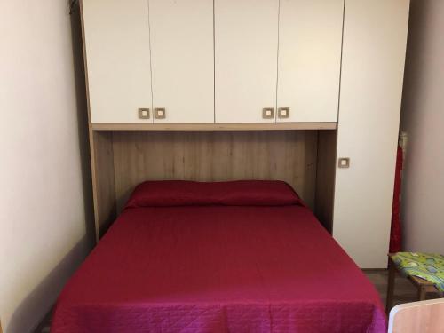 1 dormitorio con 1 cama roja y armarios blancos en Monolocale Paduledda en Cascabraga