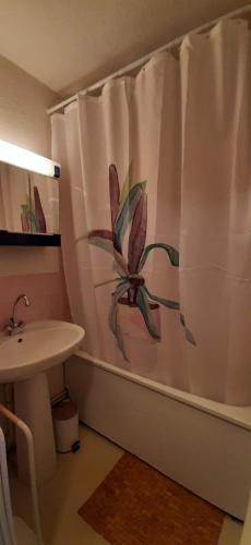 La salle de bains est pourvue d'un rideau de douche avec une fleur. dans l'établissement Un havre de paix aux pieds des chemins de montagne, aux Contamines-Montjoie