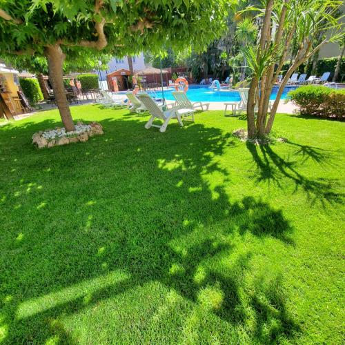 a green yard with trees and a swimming pool at Ampuria Inn in Empuriabrava