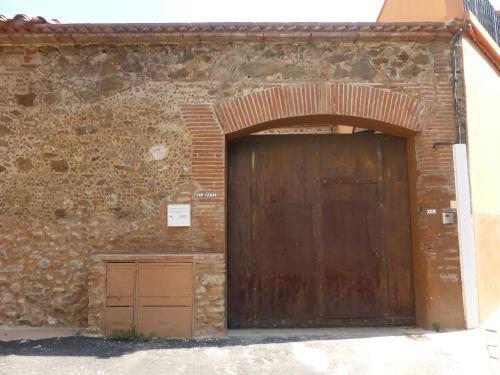 - un bâtiment en briques avec une grande porte en bois dans l'établissement El pati català, à Fourques