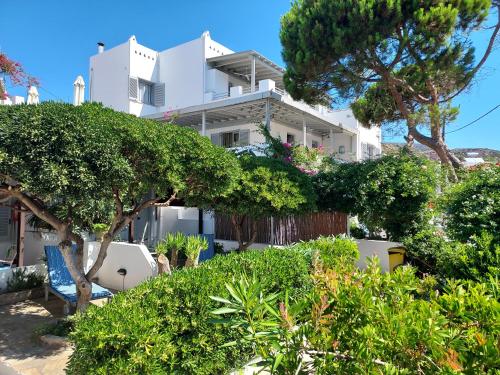 un edificio blanco con árboles delante de él en Villa Arni Andros - Βίλα ΑΡΝΗ, en Batsi