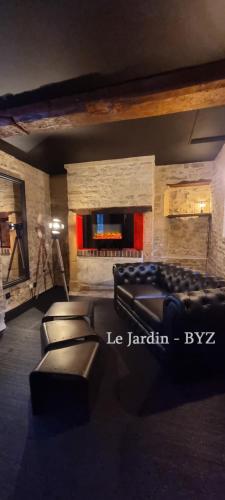ein Wohnzimmer mit Ledersofas und einem Kamin in der Unterkunft Bayeuzen Le Jardin - Nuit Romantique et Spa Privatif Bayeux in Bayeux