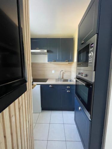 een kleine keuken met blauwe kasten en een wastafel bij Maison 6pers à 800m de la mer SAINTE-CÉCILE PLAGE in Camiers