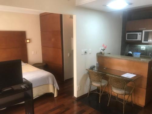 Flat em Hotel de Luxo no Itaim في ساو باولو: غرفة فندقية فيها سرير ومكتب وتلفزيون