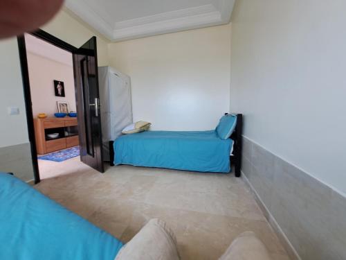 Habitación con cama azul y espejo. en Appartement vue sur mer Sidi Rahal Residence passadena II, en Casablanca