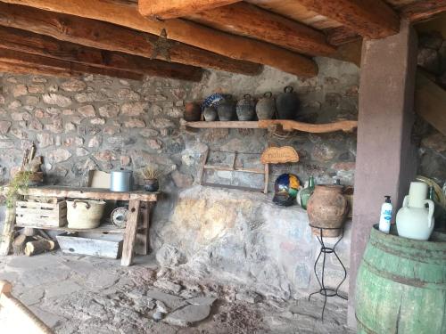 una cocina con una pared de piedra con macetas y jarrones en Casa Manel - Loft rústico con encanto, en Montcortès
