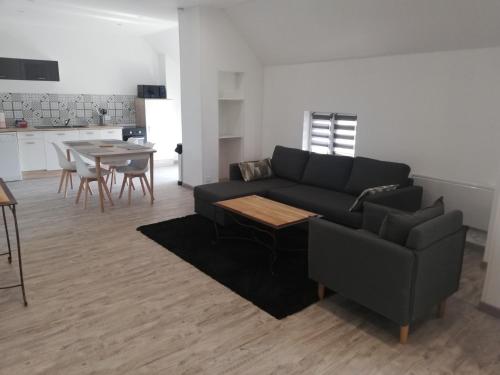 a living room with a black couch and a table at appartement neuf in Villers-Outréaux