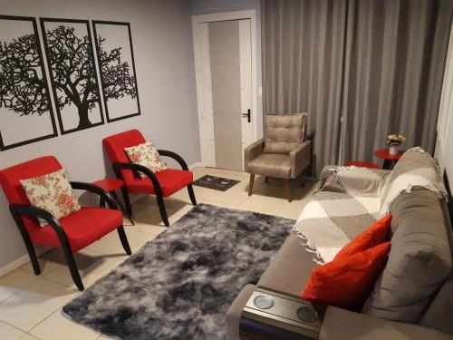 a living room with red chairs and a couch at Apartamento London - Centro Nova Petrópolis in Nova Petrópolis