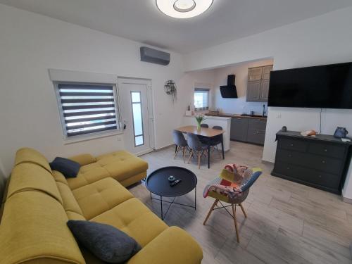 a living room with a yellow couch and a kitchen at Villa Madison in Posedarje