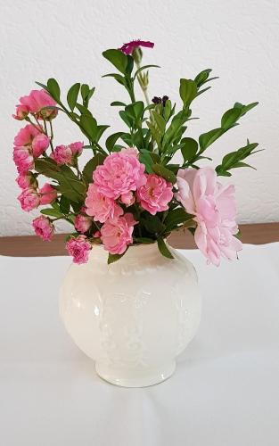 a white vase with pink flowers in it at Villa Hoffnung in Bad Elster