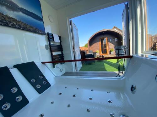Habitación con vistas a un baño con ventana grande. en Highland Stays - Ben View Studio Pod & Jacuzzi Bath en Fort William