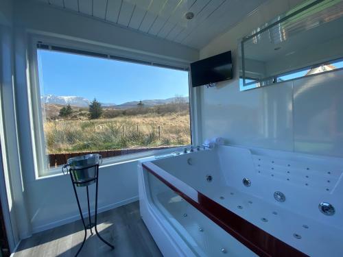 a bathroom with a tub and a large window at Highland Stays - Ben View Studio Pod & Jacuzzi Bath in Fort William