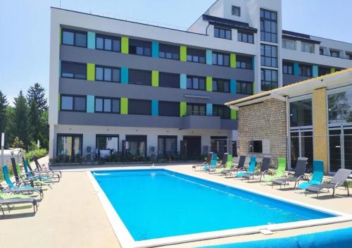 a swimming pool in front of a building at Heléna Apartman Juventus in Balatonföldvár