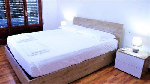 a bedroom with a large white bed with a wooden headboard at Venice Suites in Mestre