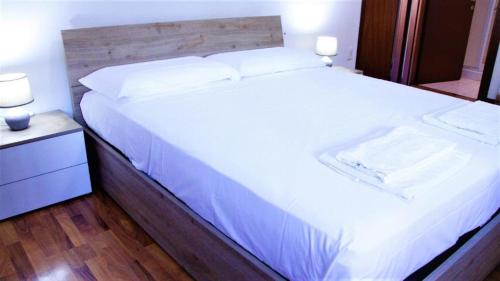 a bedroom with a large white bed with a wooden headboard at Venice Suites in Mestre