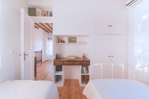 a white room with two beds and a desk at Romano garden house - land tales in Agios Romanos