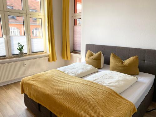 Lovely City-Apartment*Tiefgarage,Zentrum,BTU* في كوتبوس: سرير مع أغطية ومخدات صفراء في غرفة النوم