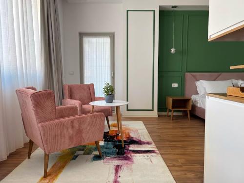 uma sala de estar com duas cadeiras, uma mesa e uma cama em Ginger Home Tirana em Tirana