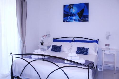 Schlafzimmer mit einem Bett mit weißer Bettwäsche und blauen Akzenten in der Unterkunft Villa Ines in Maiori