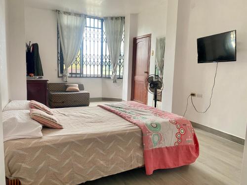 1 dormitorio con 1 cama y TV en Departamento familiar & empresarial en Machala