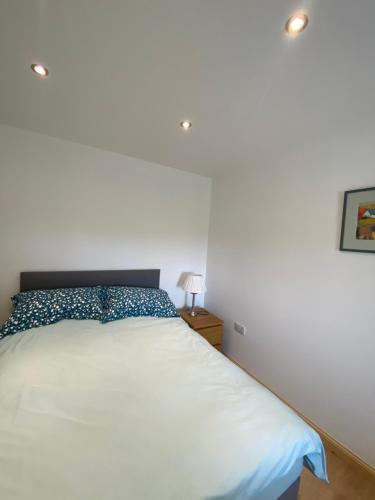 a bedroom with a white bed with a blue pillow at An Taigh Dubh- One bedroomed cottage in Creagorry