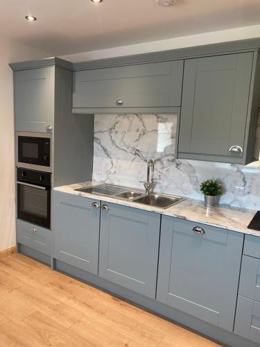 uma cozinha com armários cinzentos e um lavatório em An Taigh Dubh- One bedroomed cottage em Creagorry