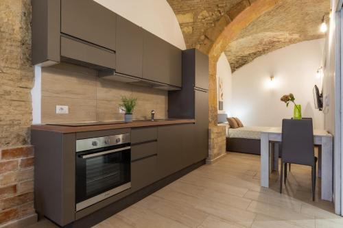 a kitchen with gray cabinets and a table and a bed at Casa Vacanza Home MAF in Cagliari