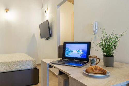 a laptop computer on a desk with a plate of bread at Casa Vacanza Home MAF in Cagliari
