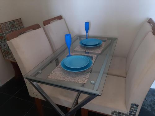 a glass table with two blue plates and utensils on it at Revigore-se e desfrute o que a vida tem de bom in São Vicente
