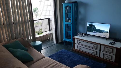 a living room with a couch and a tv on a dresser at Revigore-se e desfrute o que a vida tem de bom in São Vicente