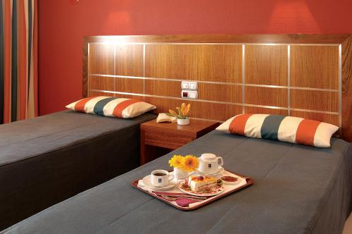 Habitación con 2 camas y bandeja de comida. en Hotel Apartamento Balaia Atlantico en Albufeira