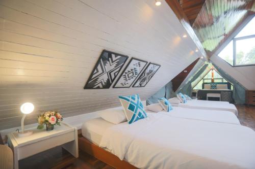 two beds in a attic room with two windows at Evergreen Pakchong Home in Pak Chong