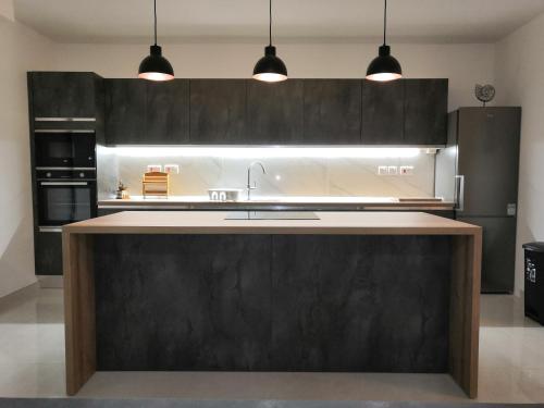 a kitchen with black cabinets and a large kitchen island at Modern, Spacious, 3 Bedroom Apartment near Malta International Airport in Luqa