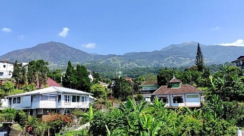 eine Gruppe von Häusern auf einem Hügel mit Bergen im Hintergrund in der Unterkunft Villa Raung Indah Tretes in Prigen