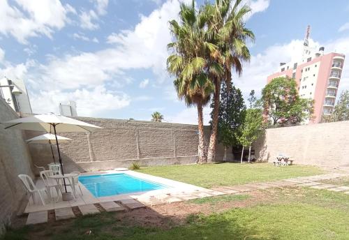 una piscina con sombrilla y palmera en Departamentos Kairos H en Mendoza