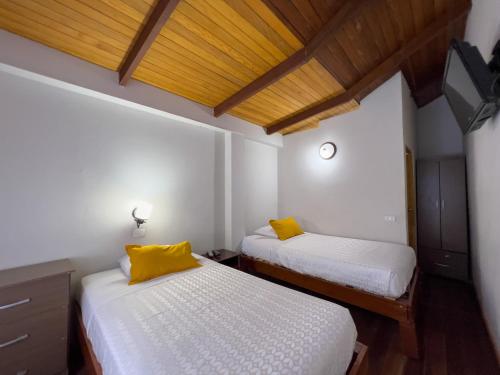two beds with yellow pillows in a room at Los Gavilanes Hotel in Pucallpa