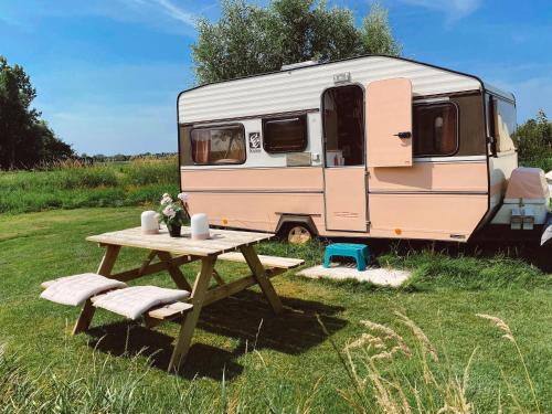 an rv parked in a field with a picnic table at Het Caravannetje B&B - retro glamping in Leidschendam