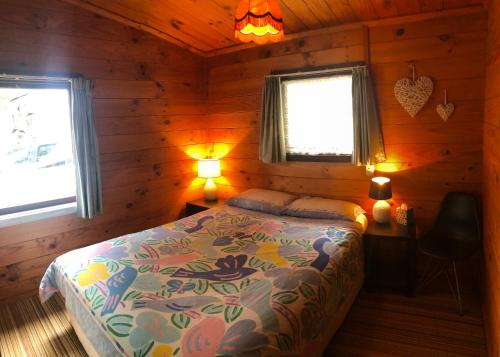 a bedroom with a bed in a wooden cabin at Tairua Treasure on Mount Paku in Tairua