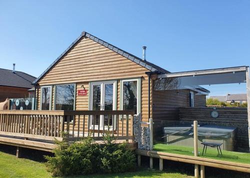 uma casa de madeira com um deque e uma mesa em Durham Coastal Lodges em Haswell