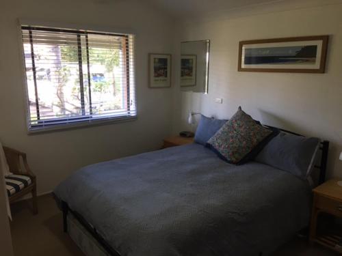 Schlafzimmer mit einem Bett mit blauer Bettwäsche und einem Fenster in der Unterkunft Wentworth Sur Le Mere in Mollymook