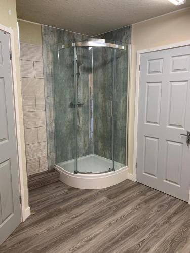 uma casa de banho com um chuveiro e uma porta de vidro em Wood Fired Hot Tub & Pergola with Glass Balcony. em Brecon