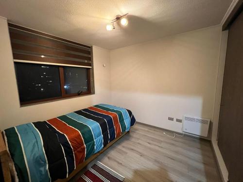 um pequeno quarto com uma cama e uma janela em Departamento amoblado Chillán Centro em Chillán