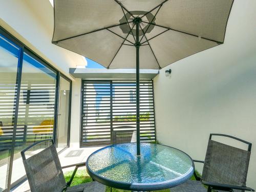 a glass table and chairs with an umbrella at Casa con alberca, coto privado, gran ubicacíon in Puerto Vallarta