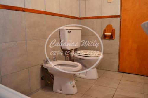 a bathroom with a toilet with a sign on the wall at Cabañas Willy in El Bolsón