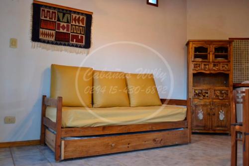 Cama en habitación con marco de madera en Cabañas Willy en El Bolsón